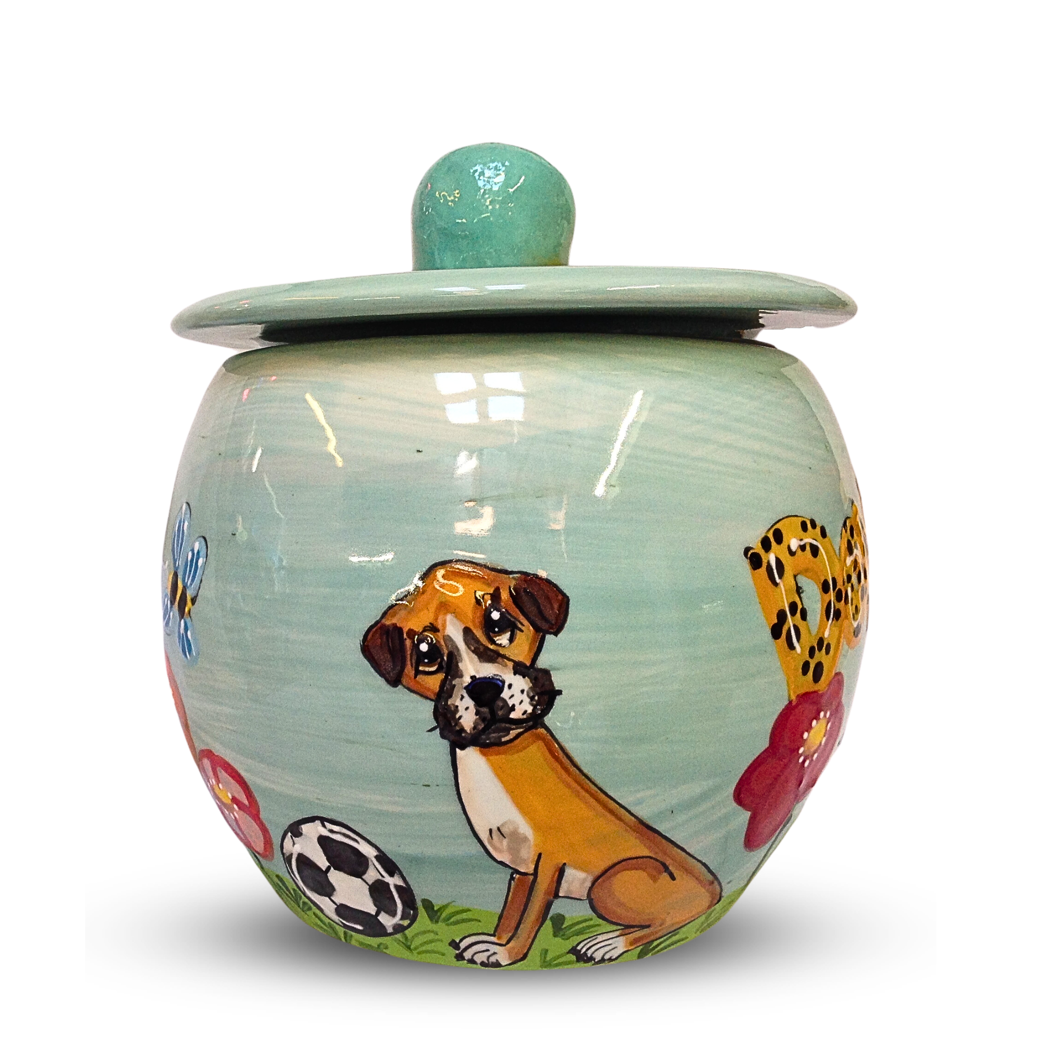 A round, hand-painted treat jar with a pastel blue lid, featuring a charming pup and colorful paw prints amidst a backdrop of grass and soccer balls