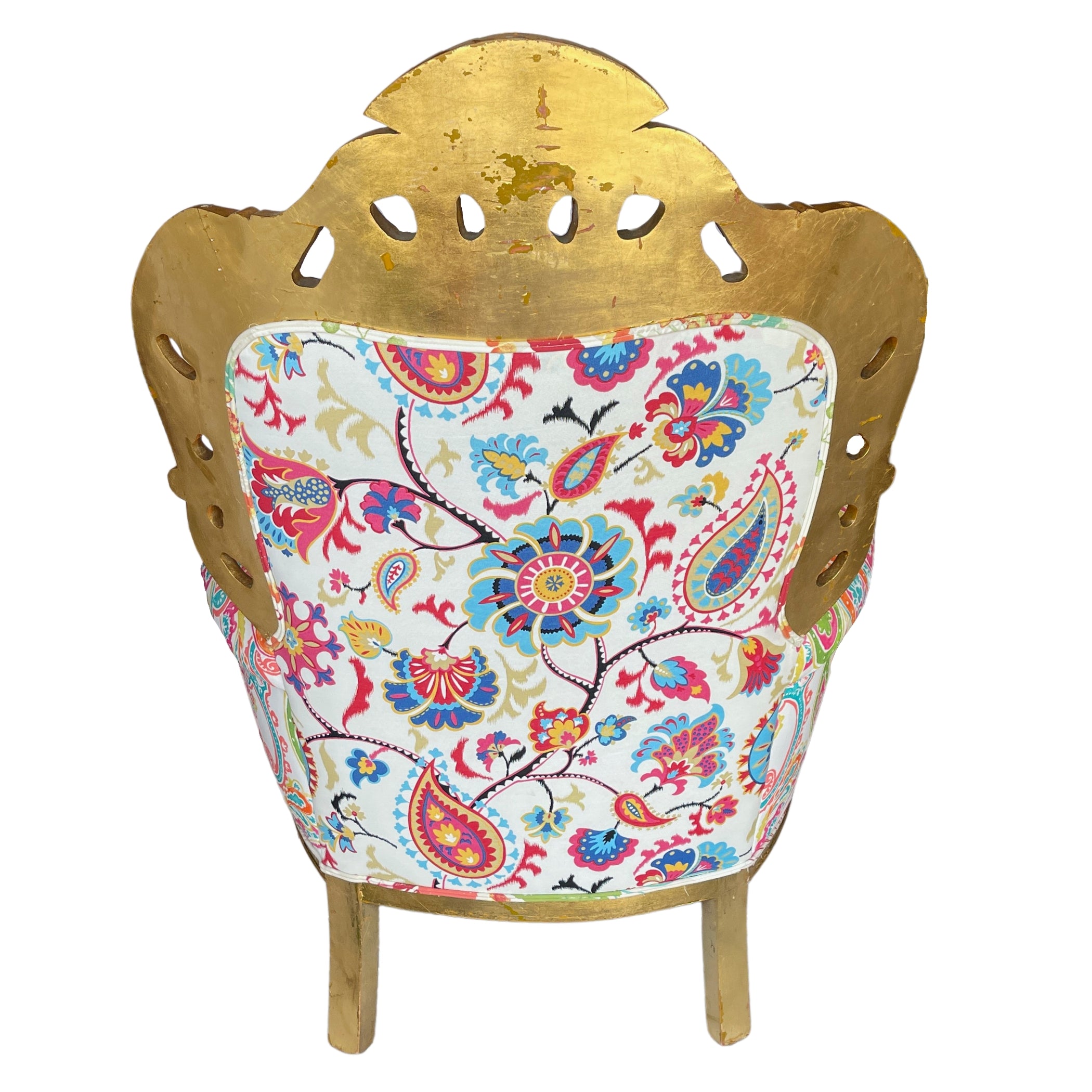 Back view of a gold-framed baroque armchair, with visible wear on the gold patina, featuring a cut-out design on the crest and a white fabric with a vibrant, multi-colored floral and paisley pattern