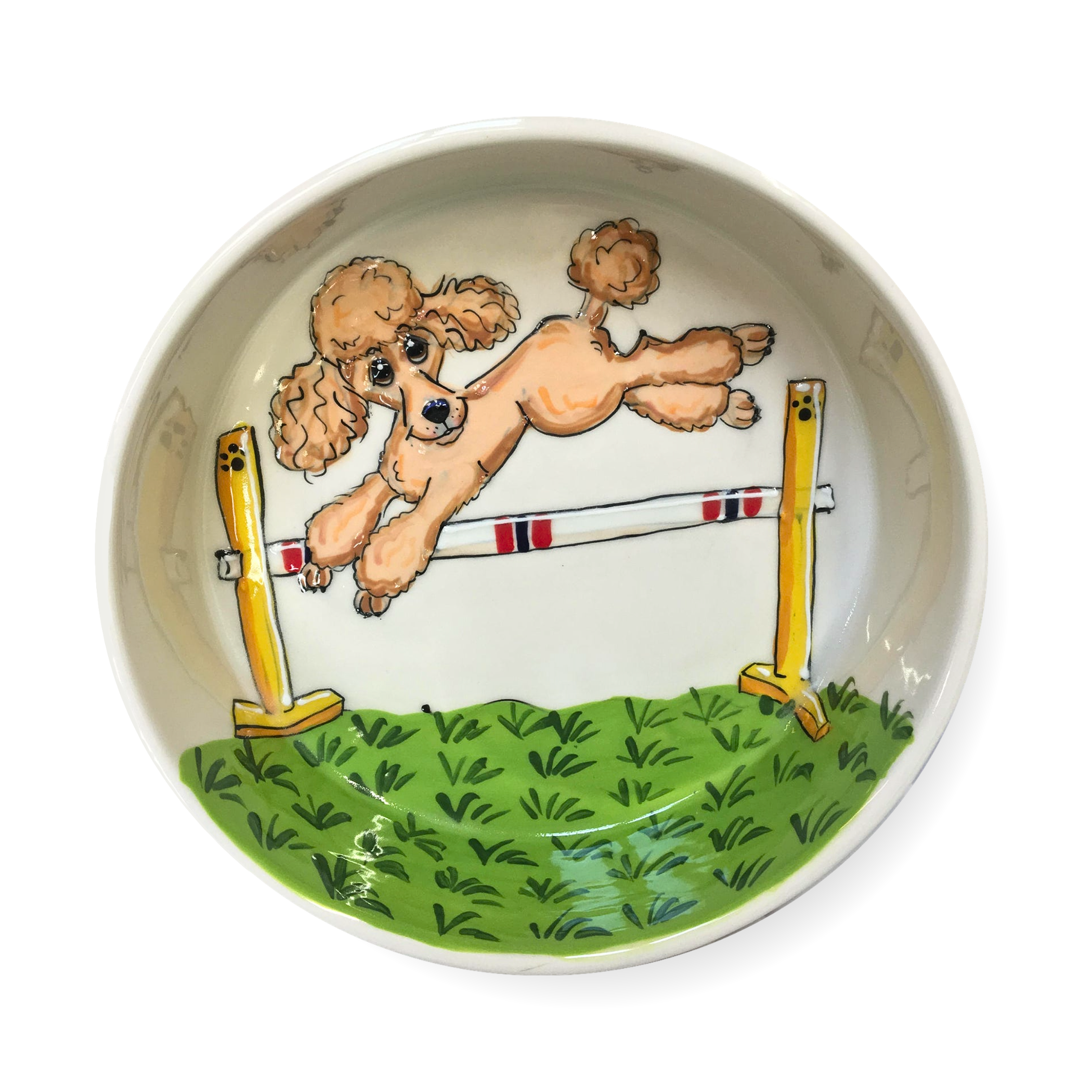 Illustrated ceramic bowl featuring a dynamic scene of a tan poodle leaping over an agility jump hurdle. The background is painted in light green with detailed grass texture, simulating an agility course field. Two yellow agility poles with red and white stripes support the jump, enhancing the action-packed design of this kitchenware item