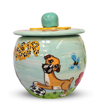 Artisanal treat jar painted with a frolicsome dog, leopard spots, and whimsical insects, topped with a pastel blue lid adorned with a sunny yellow accent