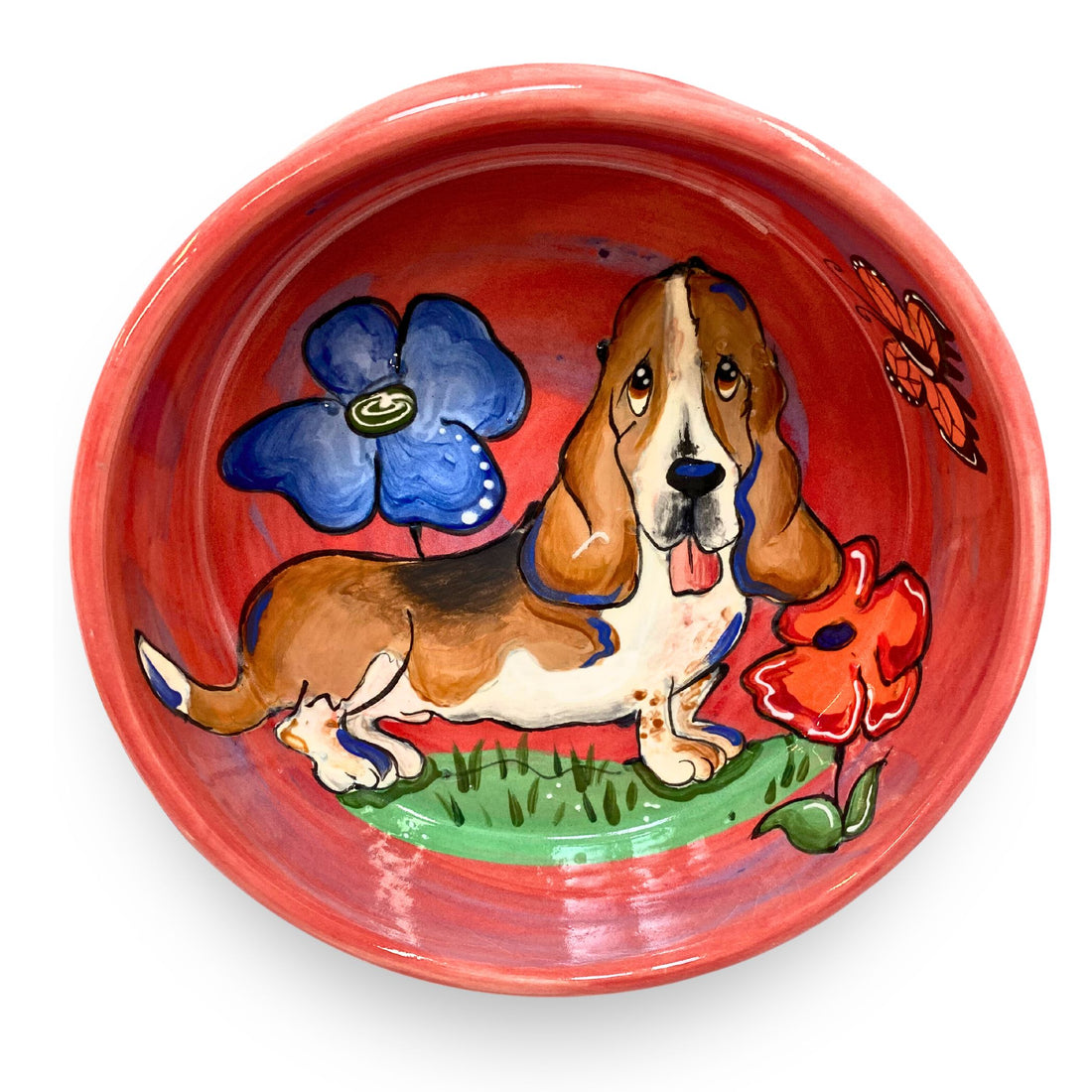 Hand-painted ceramic bowl featuring a basset hound and colorful flowers on a red background, showcasing artistry and craftsmanship