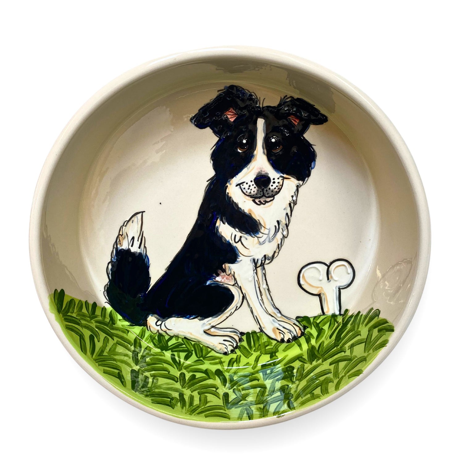 Hand-painted ceramic bowl displaying a Border Collie sitting in a vibrant green grassy field, from FauxPaw&