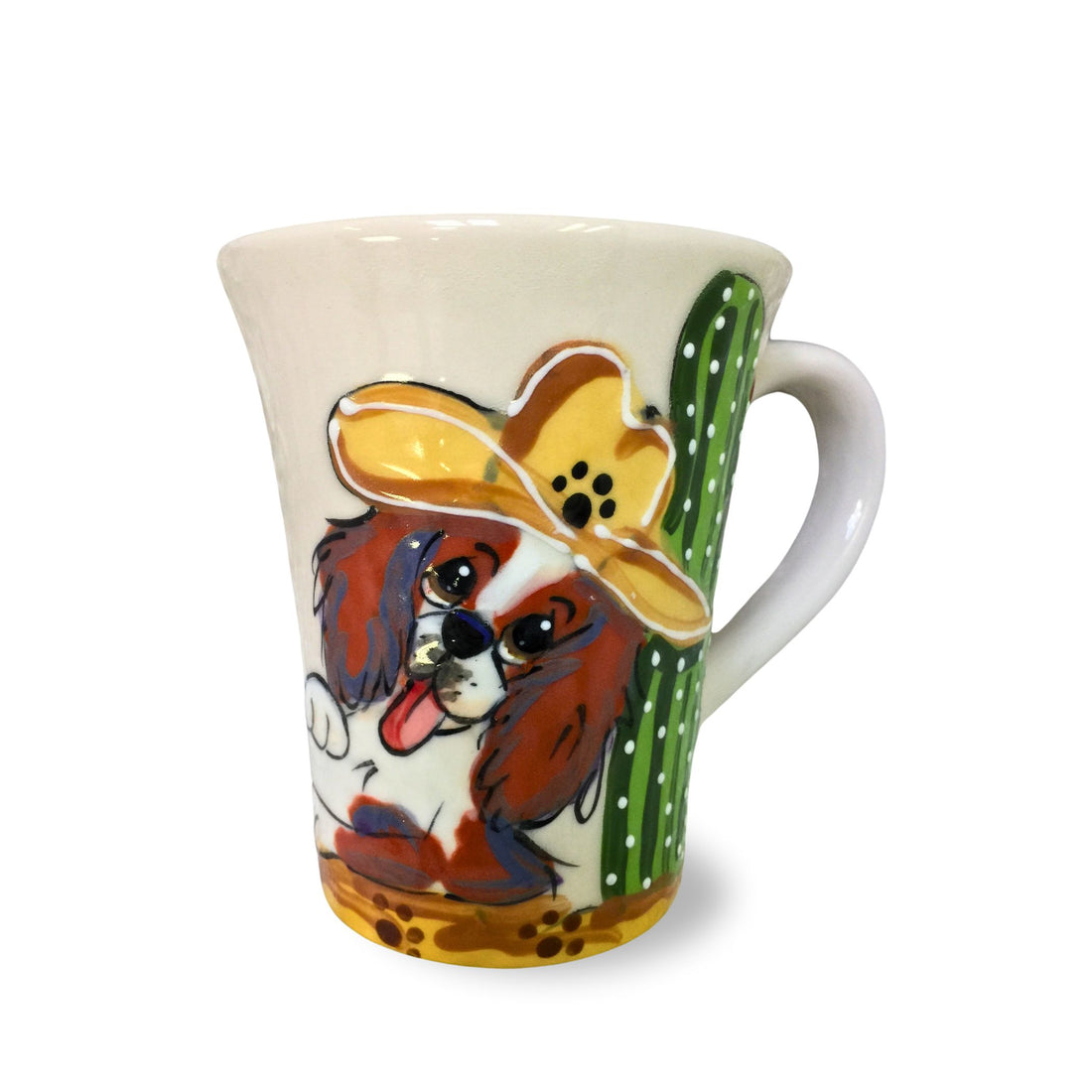 A 12 oz coffee mug with a whimsical hand-painted Cavalier King Charles Spaniel wearing a cowboy hat beside a green cactus, created by Debby Carman.