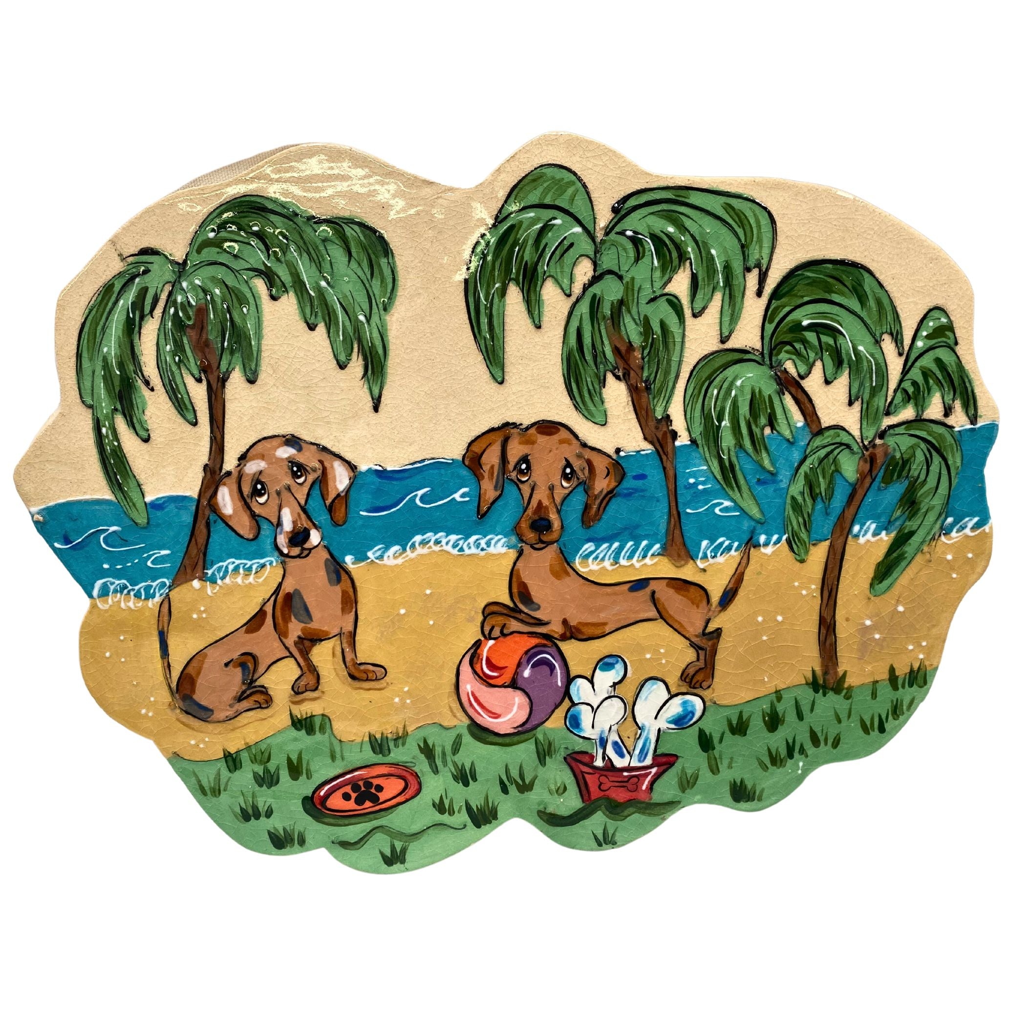 Handmade ceramic tile featuring two dachshunds hand-painted in a whimsical style, set on a beach scene with palm trees and playful beach accessories, crafted by artist Debby Carman