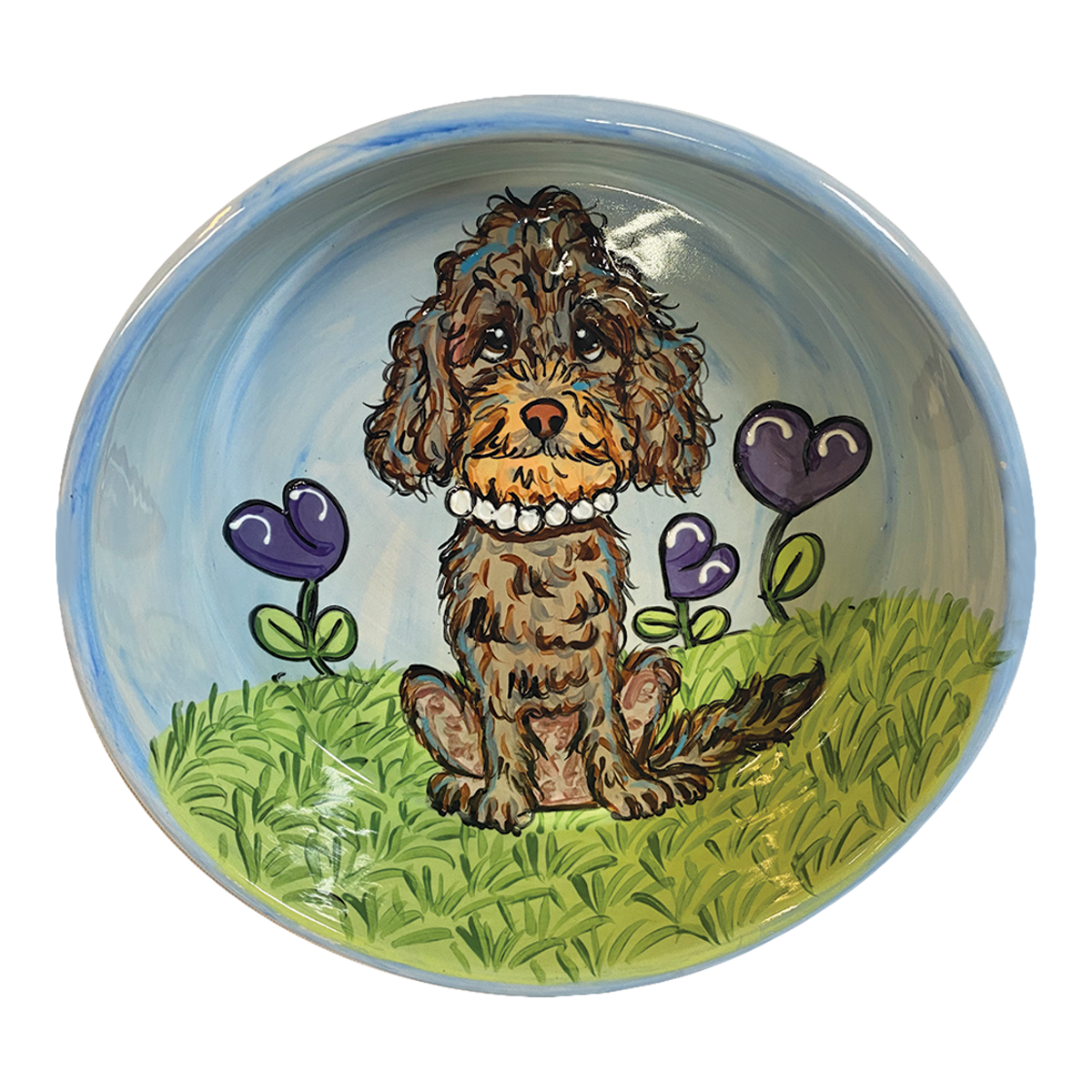 Charming hand-painted ceramic bowl with a glossy finish, depicting a brown poodle sitting in a vibrant green grassy field with purple heart-shaped flowers. The background transitions from the greenery of the field to a serene blue sky, creating a picturesque garden setting that exudes a loving, homely vibe.