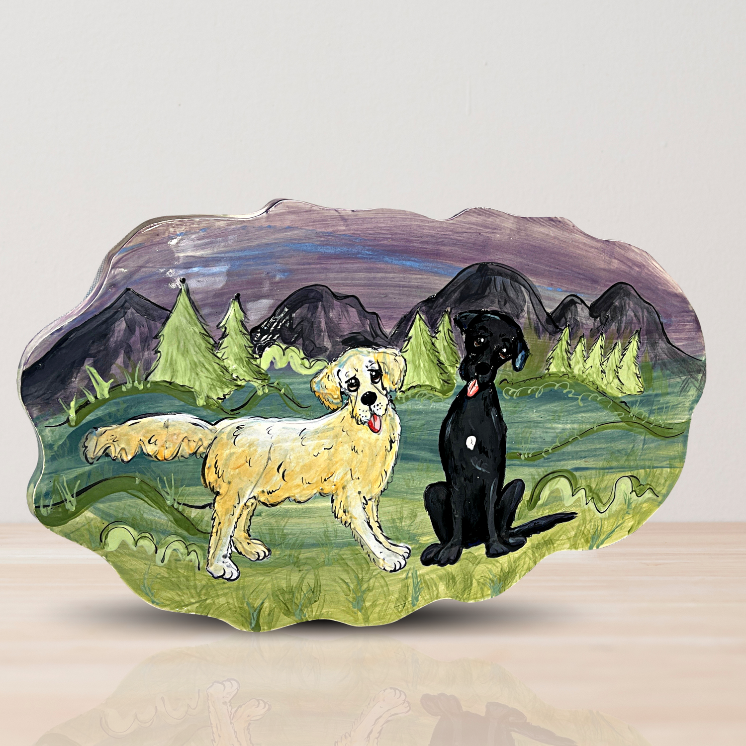 Handcrafted ceramic tile with a custom hand-painted portrait of two dogs, one golden and one black, against a mountainous landscape, created by artist Debby Carman