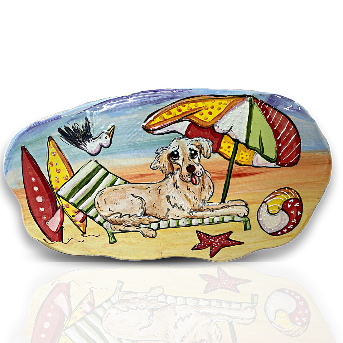 Handmade ceramic tile with a whimsical painting of a dog relaxing on a beach chair under an umbrella, with surfboards and a seagull flying by, created by artist Debby Carman