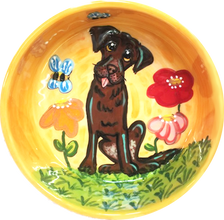 photo of custom ceramic dog bowl with hand painted portrait of chocolate Labrador in garden with flowers and bees on orange bowl handmade by debby carman artist of faux paw productions petique artique